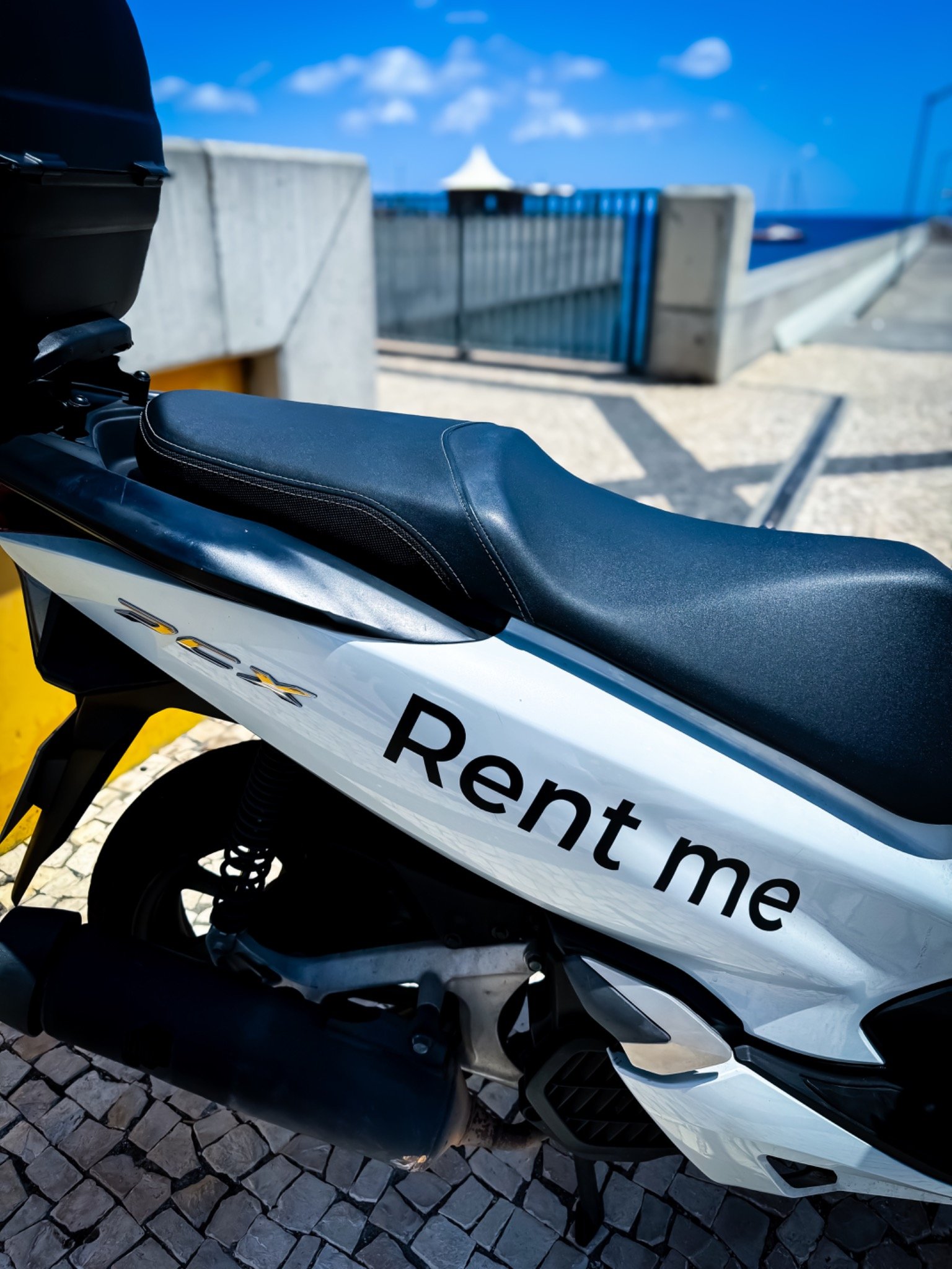 White Honda PCX seat and rear storage box beside the sea