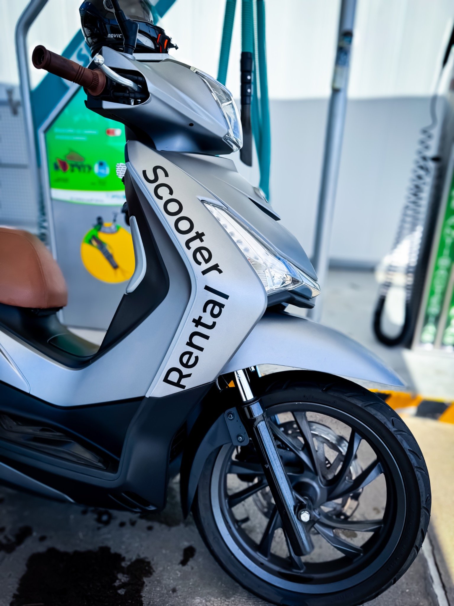 Silver rental scooter with a brown seat and helmet